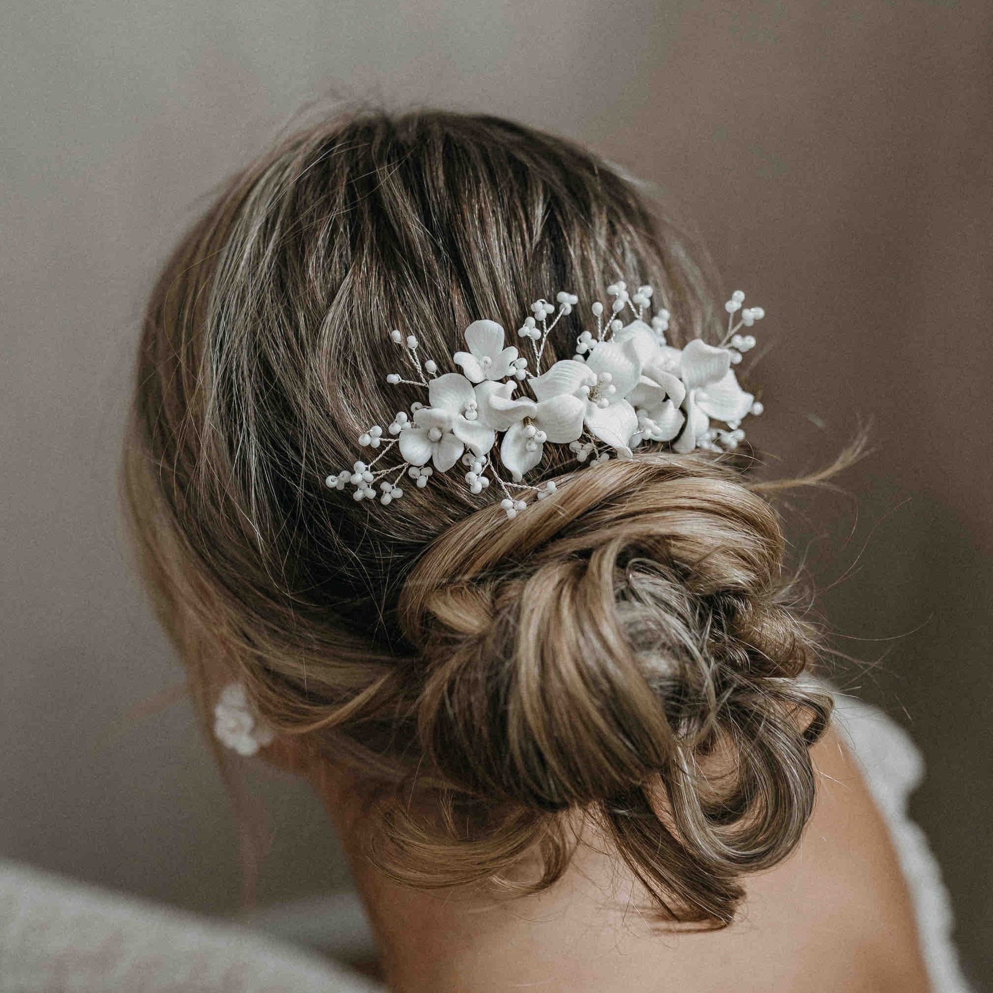 Eine Frau mit hochgestecktem Haar, geschmückt mit einem zarten Fräulein Maya Keramik Haarkamm mit Blumen und Perlen.