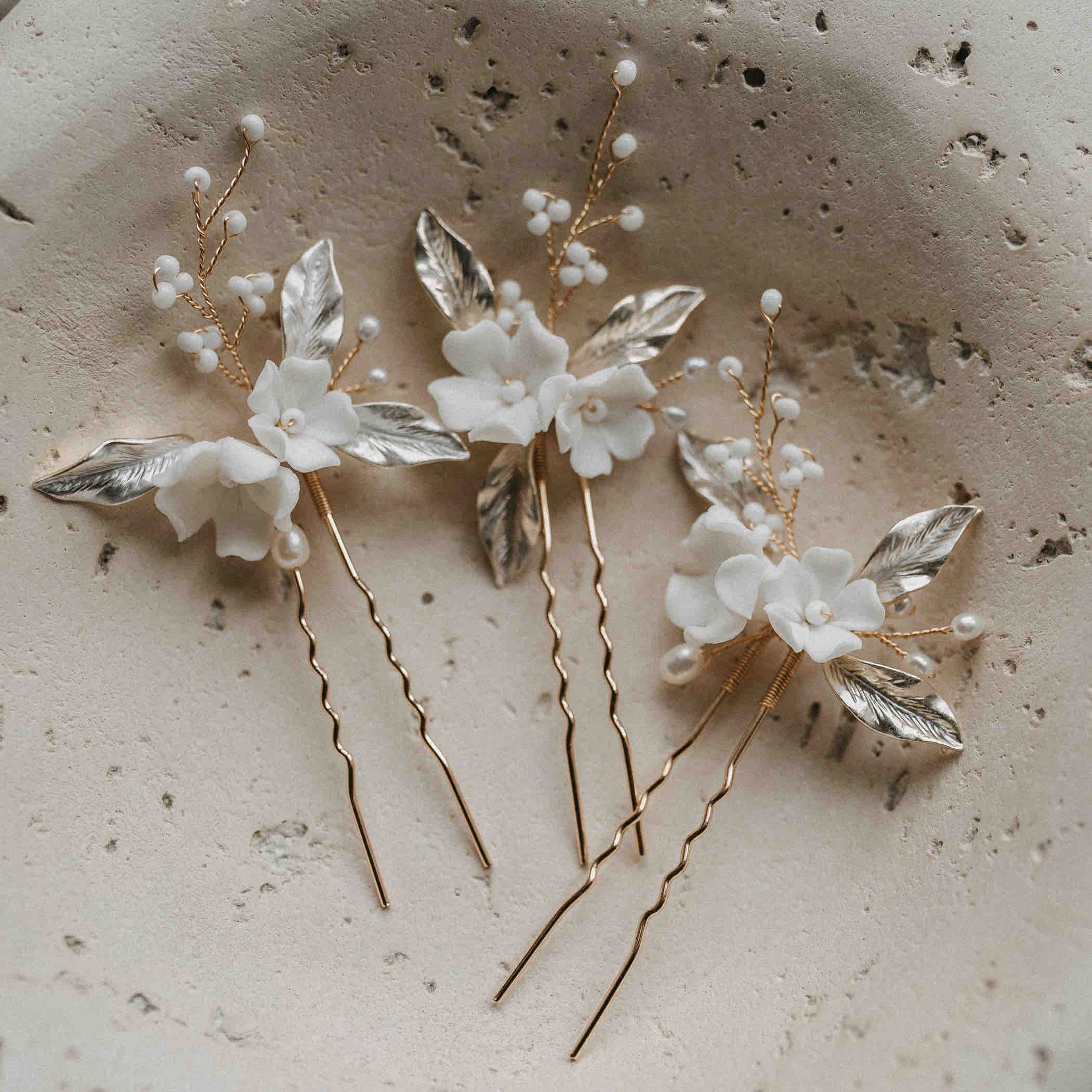 Drei Haarnadeln mit Keramik Blumen und Blätter (3 Stück) von Fräulein Maya, mit goldenen Stielen, weißen Blumen, Süßwasserperlen und silbernen Blättern, bieten eine elegante, naturinspirierte Brautfrisur.
