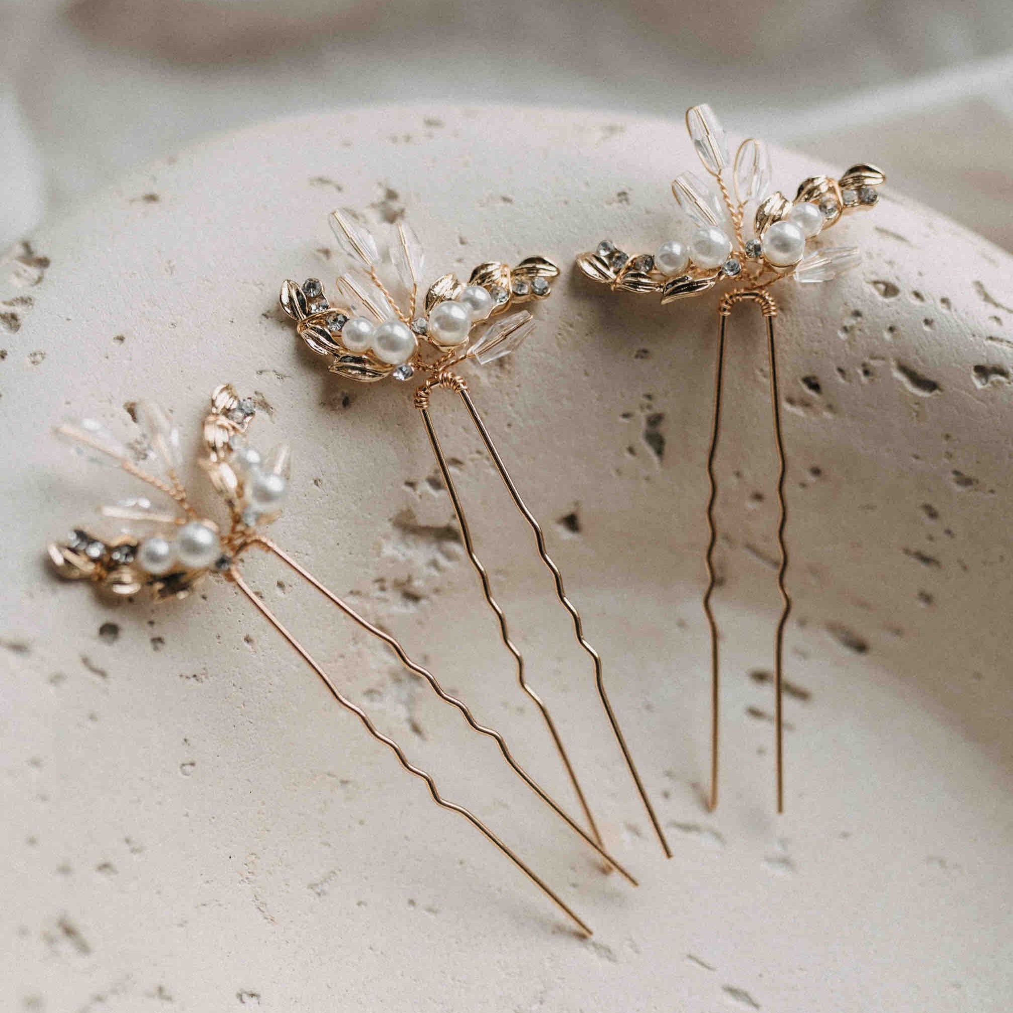 3er Set Kristall Haarnadeln mit funkelnden Steinen von Fräulein Maya - glitzernde Haarnadeln, perfekt als eleganter Haarschmuck für die Hochzeit. Stilvoll präsentiert auf einer strukturierten, beigen Keramikfläche.